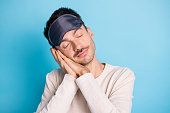 Portrait of nice peaceful brunet guy wearing eye mask sleeping calm drowsiness isolated over bright blue color background
