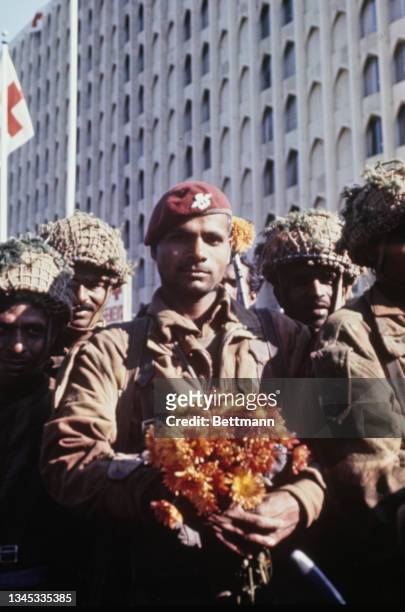 Indian soldiers holding flowers as they halt outside the 'neutral' Intercontinental Hotel where diplomats and foreigners took refuge, Dacca,...