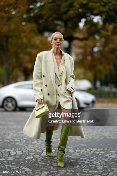 Leonie Hanne wears Valentino sunglasses, a pastel green long wool coat, a pastel green oversized blazer jacket, white bras, a mini Hermes Kelly bag,...
