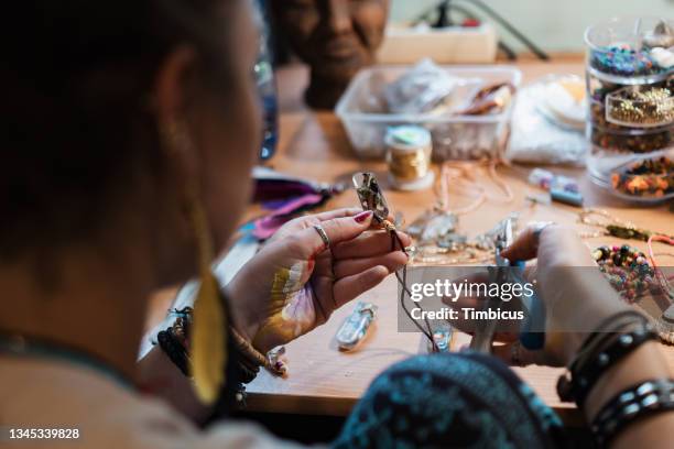 talented young woman using pliers while adjsuting and making handmade custom jewlery - bijuteria imagens e fotografias de stock