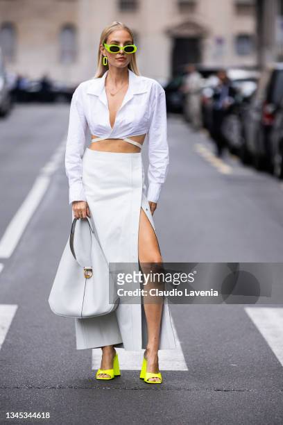 Leonie Hanne, wearing a white crop shirt, grey leather long skirt, neon green mules, grey Ferragamo bag and neon green Gucci sunglasses, poses ahead...
