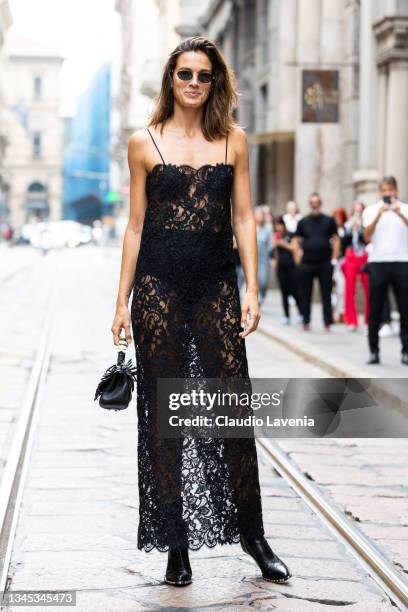 Chiara Baschetti, wearing a black sheer lace dress and black bag, poses ahead of the Ermanno Scervino fashion show during the Milan Fashion Week -...
