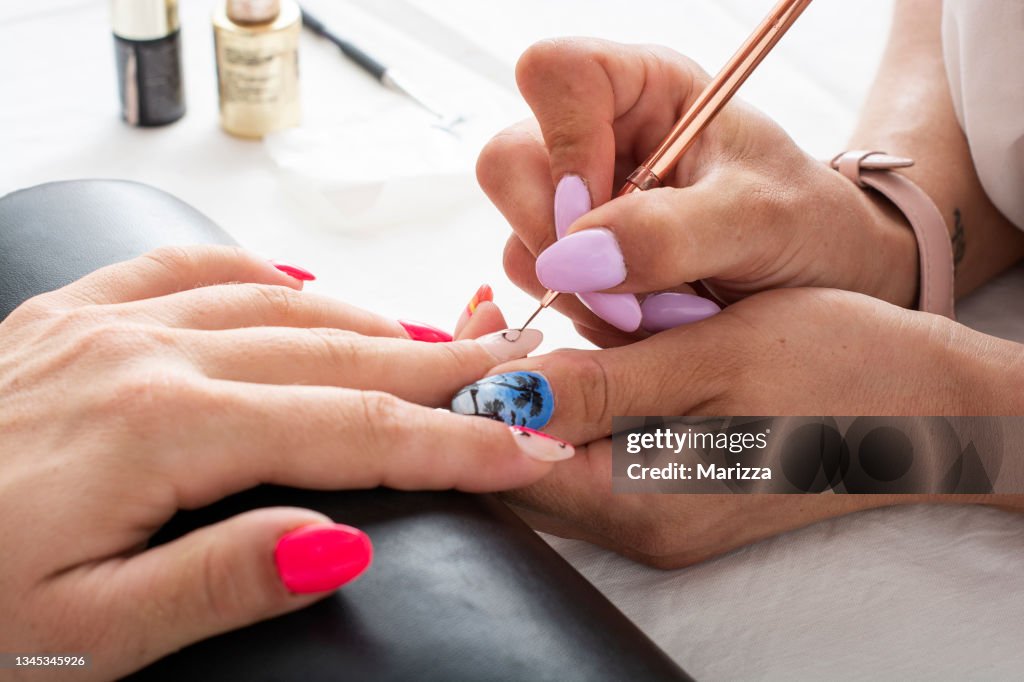 Woman getting her nails done in salon by manicure worker
