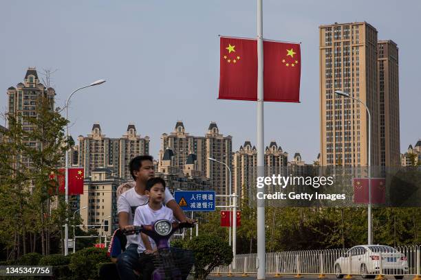 Residents cycle through the Evergrande city during the last day of the National Day and Golden Week holidays on October 7, 2021 in Wuhan, Hubei...
