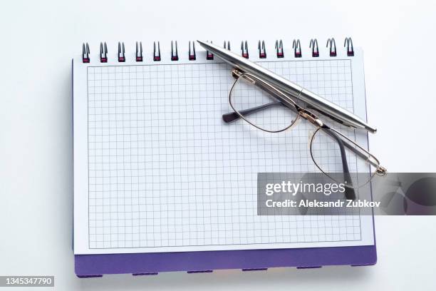 the pen and glasses are lying on an open notebook. a blank sheet of notepad with the notes of a businessman or freelancer. the concept of financial statements, the calculation of profit or loss of the enterprise, the management of expenses and income. - russian literature stock pictures, royalty-free photos & images