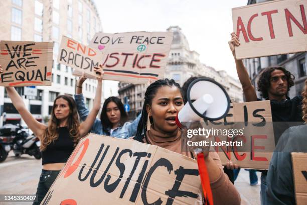 joven gritando en megáfono durante una protesta - antirracismo fotografías e imágenes de stock