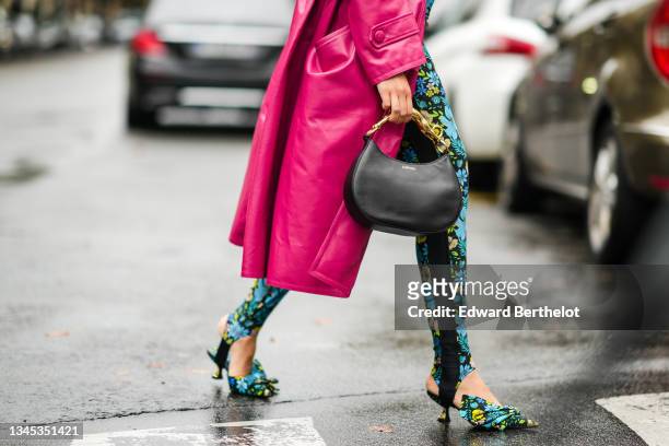 Susanna Lau wears a pink shiny vinyl long trench coat, a blue and yellow floral print jumpsuit, a black Lanvin leather bag, pointed shoes with floral...