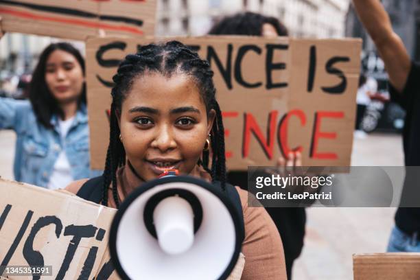 joven gritando en megáfono durante una protesta - blm fotografías e imágenes de stock