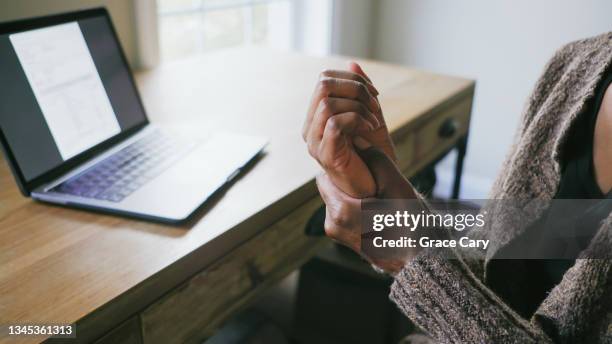 woman holds hand in pain - carpaletunnelsyndroom stockfoto's en -beelden