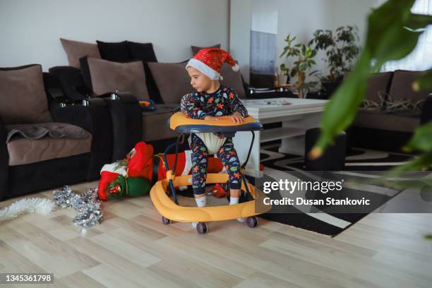 playful toddler boy in a baby walker, playing with christmas ornaments - baby walker stock pictures, royalty-free photos & images