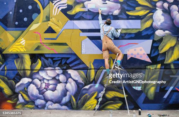 artista di strada su una scala che disegna sul muro - arts culture and entertainment foto e immagini stock