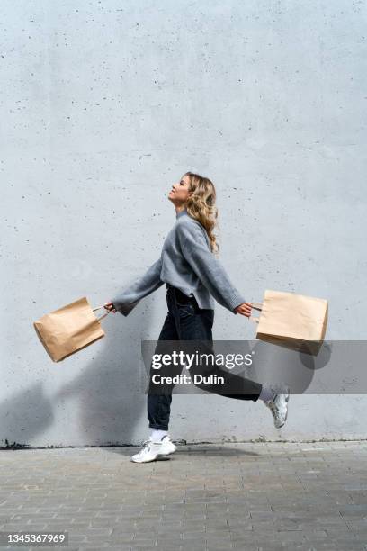 woman walking along street with two shopping bags - shopper bag fotografías e imágenes de stock