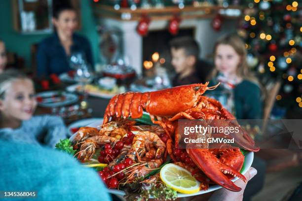 familie mit weihnachtsessen mit lachsfischfilet, jakobsmuscheln, hummer, garnelen und weihnachtskuchen - lobster stock-fotos und bilder