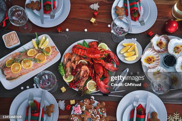family having christmas dinner with salmon fish fillet, scallops, lobster, shrimps and christmas cake - fish dinner stock pictures, royalty-free photos & images