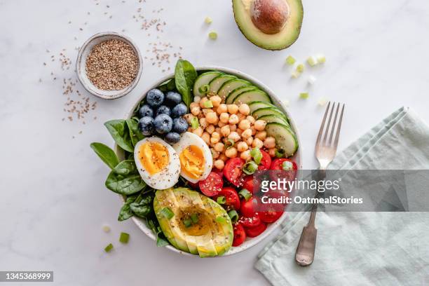 buddha bowl with avocado, egg, chickpeas, tomato, cucumber, spinach and blueberries - bowl photos et images de collection
