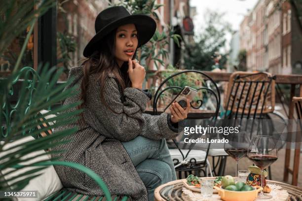 a brunette woman enjoying the warm restaurant culture in a bar - hague market stock pictures, royalty-free photos & images