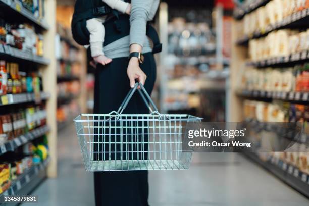 cropped shot of mother carrying a shopping cart, doing grocery shopping in supermarket - buying photos et images de collection