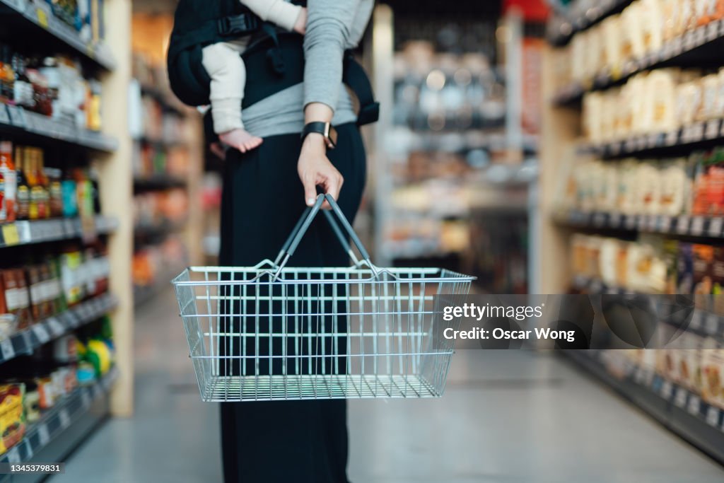 Cropped shot of mother carrying a shopping cart, doing grocery shopping in supermarket