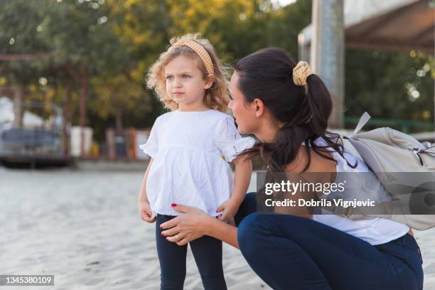 verängstigtes junges mädchen, das in die ferne schaut und mutter beruhigt sie - trotzanfall stock-fotos und bilder