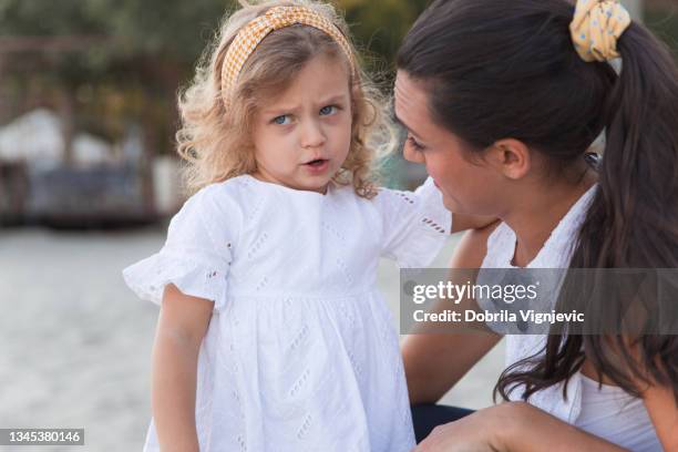 sad toddler hugging her mom and looking scared at the playground - frowning stock pictures, royalty-free photos & images