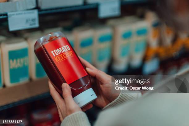 close-up of young woman doing grocery shopping in supermarket, holding a bottle of ketchup - ketchup bildbanksfoton och bilder