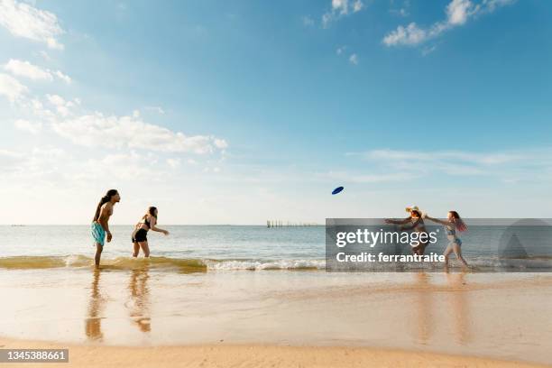 familia jugando frisbee en la playa - frisbee fotografías e imágenes de stock