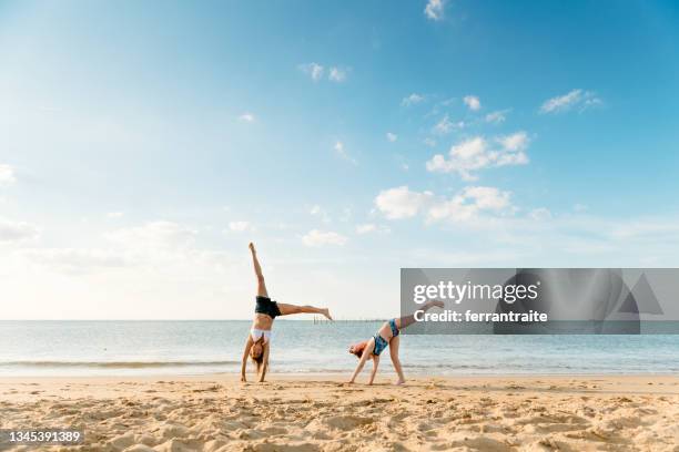 madre e hija haciendo ruedas de carro en la playa - vacaciones de sol y playa fotografías e imágenes de stock