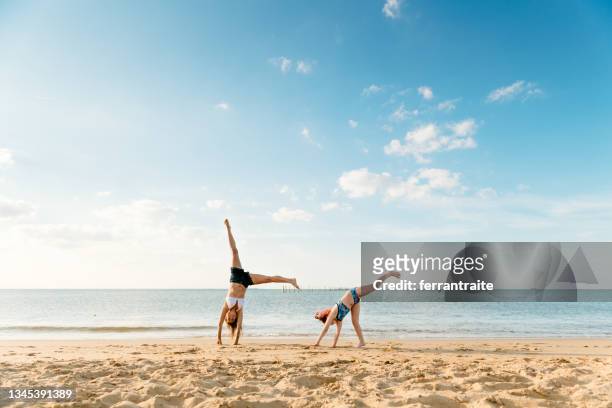 mother and daughter doing cartwheels at the beach - beach holiday stock pictures, royalty-free photos & images