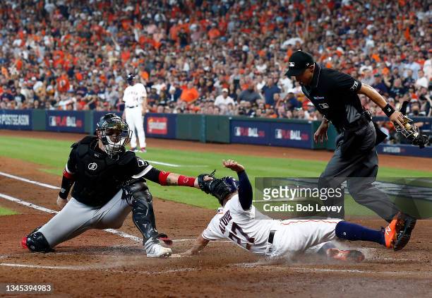 Jose Altuve of the Houston Astros slides safely past the tag of Yasmani Grandal of the Chicago White Sox to score during the 3rd inning of Game 1 of...