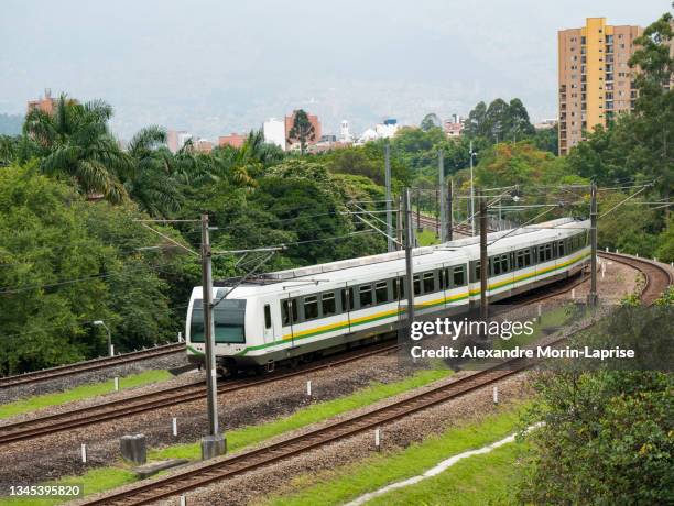 subway that passes through the railroad surrounded by trees - metro medellin stock pictures, royalty-free photos & images