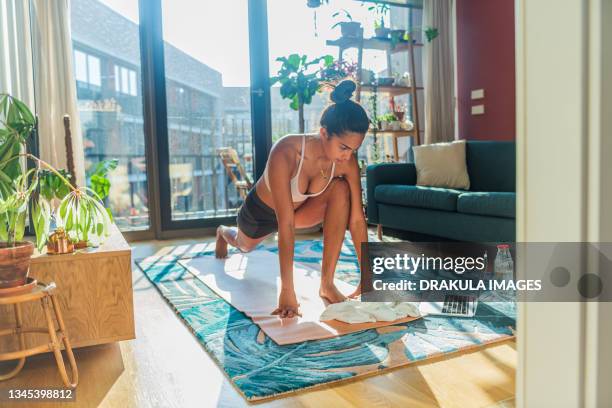 woman doing online yoga class with laptop at home - home workout foto e immagini stock