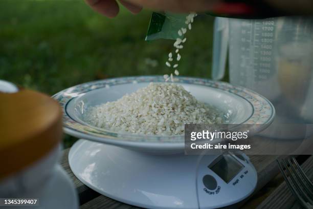 an amount of rice is being weighed over a white plate by using a digital scales. some rice is putted onto a plate for weight measurements over a digital scale. - mass unit of measurement stock pictures, royalty-free photos & images
