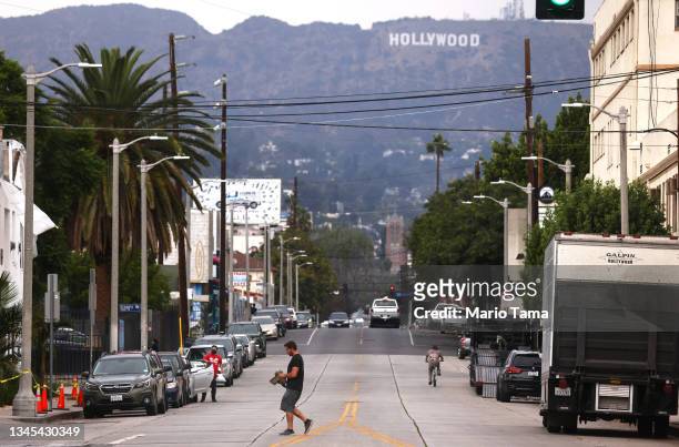 Pedestrian crosses a street in front of the Hollywood sign on October 07, 2021 in Los Angeles, California. The IATSE union which represents...
