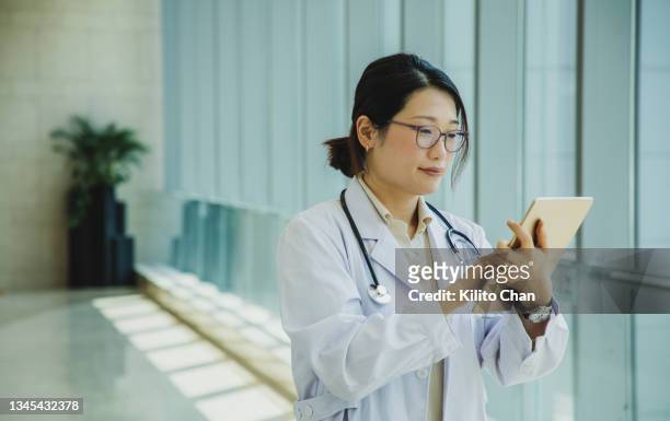 portrait of asian female doctor using digital tablet in the hospital corridor - china exam stock pictures, royalty-free photos & images