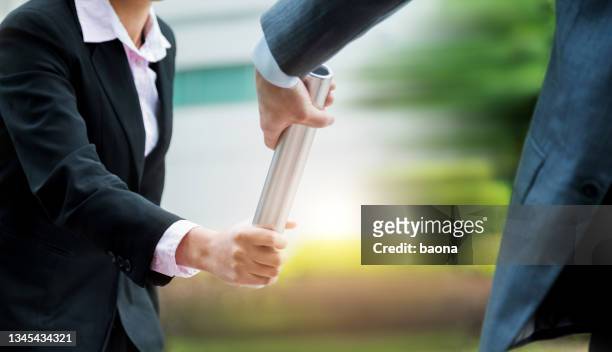 business people pass the baton outdoors - continuity stockfoto's en -beelden