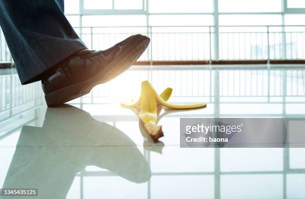 businessman stepping on banana peel - stumble stock pictures, royalty-free photos & images