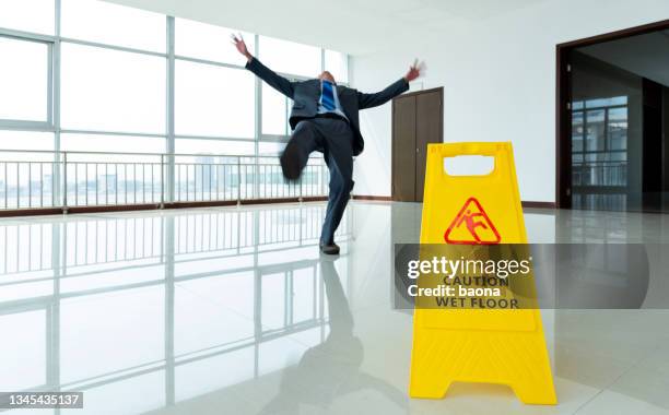 businessman slipping by the warning sign - gevallen stockfoto's en -beelden
