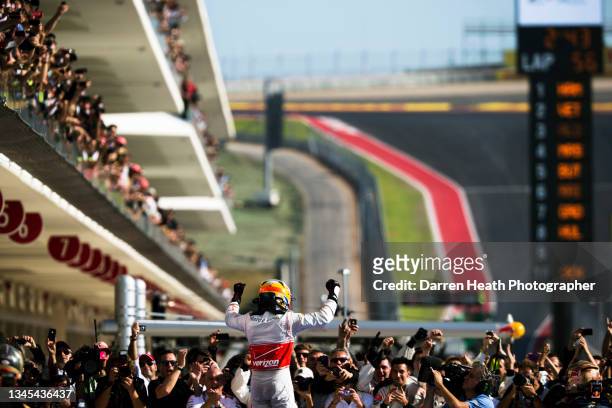British McLaren Formula One team racing driver Lewis Hamilton standing on his MP4-27 racing car in Parc Fermé raises his arms and clenches his fists...
