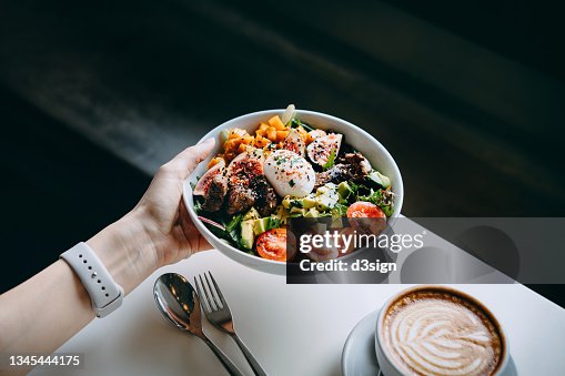 Close up of woman's hand holding a bowl of fresh beef cobb salad, serving on the dining table. Ready to enjoy her healthy and nutritious lunch with coffee. Maintaining a healthy and well-balanced diet. Healthy eating lifestyle Close up of woman's hand holding a bowl of fresh beef cobb salad, serving on the dining table. Ready to enjoy her healthy and nutritious lunch with coffee. Maintaining a healthy and well-balanced diet. Healthy eating lifestyle