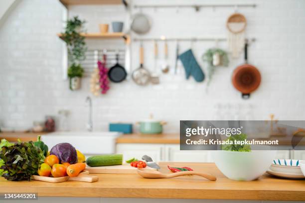 küchentisch mit gemüse und schneidebrett für die zubereitung von salat. - kitchen stock-fotos und bilder