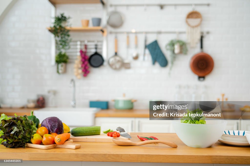 Kitchen table with vegetables and cutting board for preparing salad .