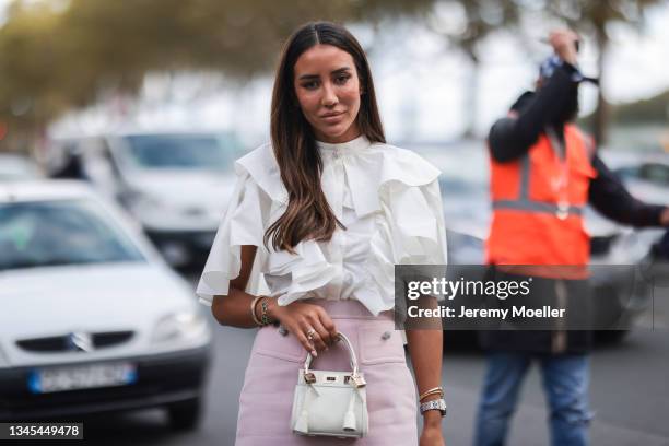 Tamara Kalinic wearing white blouse, pink skirt, silver heels and white bag outside Giambattista Valli Show on October 04, 2021 in Paris, France.