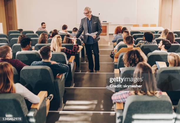 felice professore maschio che dà ai suoi studenti i risultati dei test in anfiteatro. - white male professor foto e immagini stock