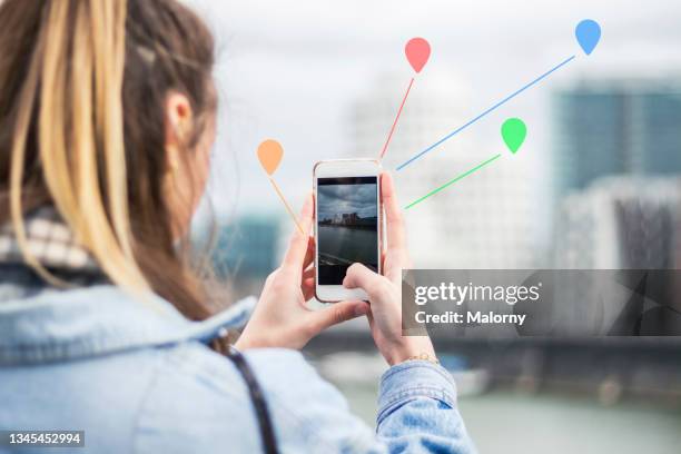 young woman outdoors in the city, data emerging from her phone. - hologram city stock pictures, royalty-free photos & images