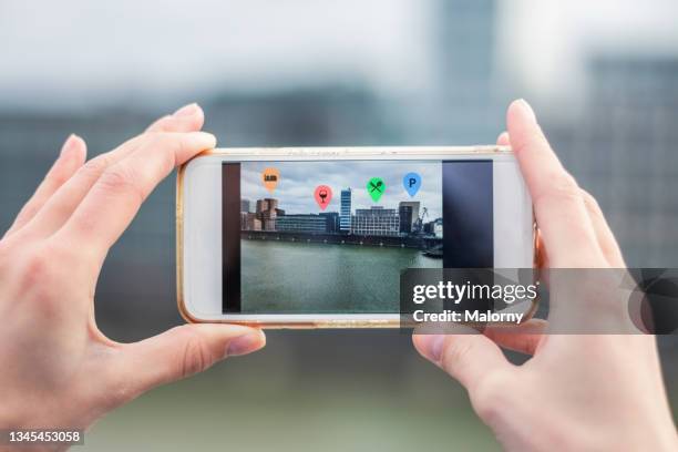 young woman outdoors in the city, data emerging from her phone. - smartphone hologram stockfoto's en -beelden