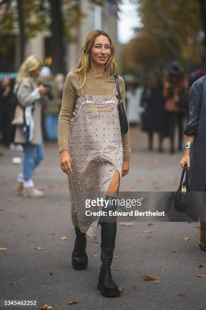 Alexandra Golovanoff wears a beige wool pullover, a beige suede gold and silver nailed / studded ruffled borders slit / split midi dress, a black...