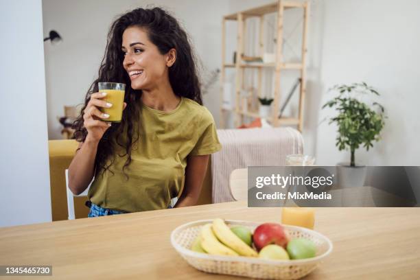 porträt einer glücklichen jungen frau, die zu hause saft genießt und trinkt - drinking juice stock-fotos und bilder