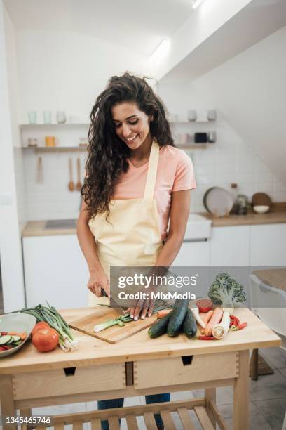 portrait of a beautiful vegan chopping vegetables at home - chopping vegetables stock pictures, royalty-free photos & images