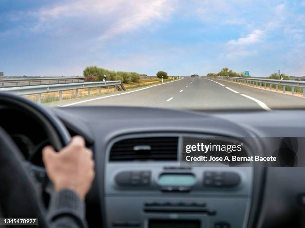 car point of view, young man driving a car on a two-lane highway. - autoperspektive stock-fotos und bilder