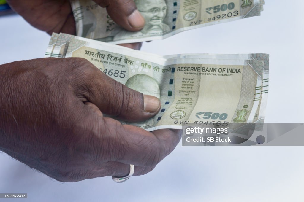 Business Man hand counting five hundred Indian rupee note. High angle view. Close up. White background. Business Finance activity Backgrounds.